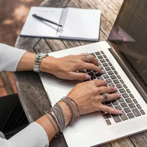 Woman's hands typing on a MacBook laptop.